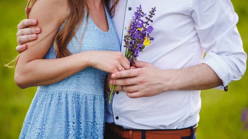 Pareja sosteniendo un ramo de flores moradas